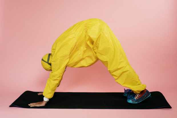 person in yellow protective suit doing a yoga pose